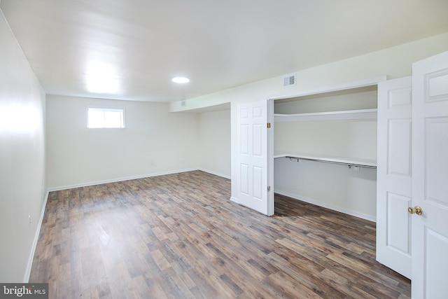 basement featuring visible vents, baseboards, and wood finished floors