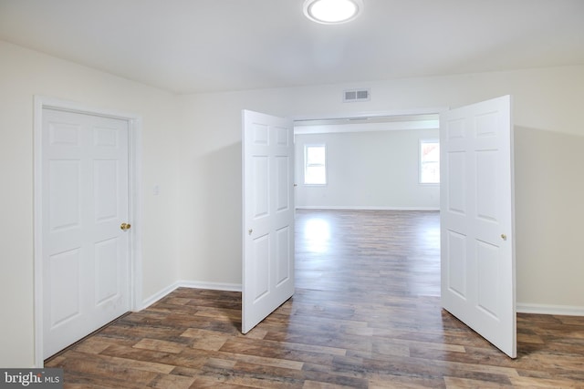 unfurnished room featuring wood finished floors, visible vents, and baseboards