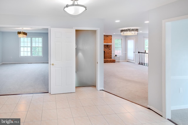 unfurnished bedroom featuring tile patterned flooring, a notable chandelier, multiple windows, and carpet flooring