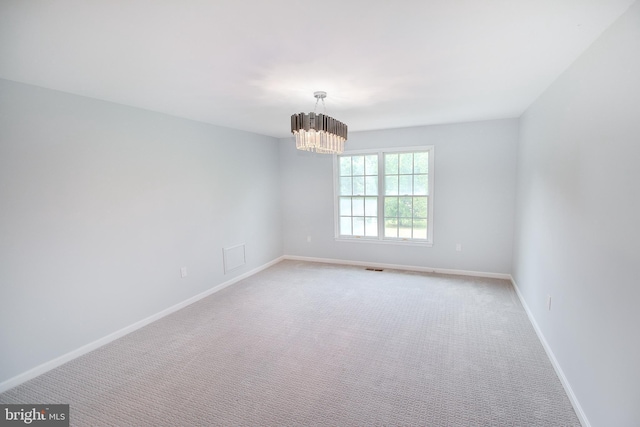 unfurnished room featuring visible vents, a notable chandelier, light colored carpet, and baseboards