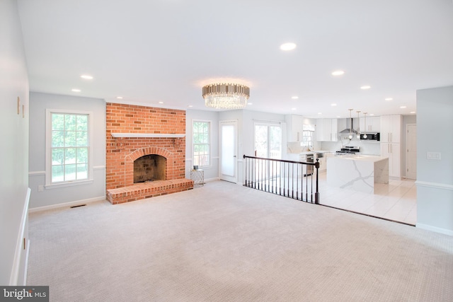 unfurnished living room with visible vents, plenty of natural light, and light colored carpet