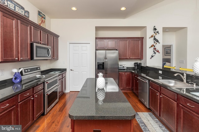 kitchen featuring dark stone counters, dark hardwood / wood-style flooring, a center island, sink, and appliances with stainless steel finishes