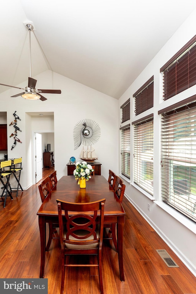 dining space with ceiling fan, dark hardwood / wood-style flooring, and vaulted ceiling