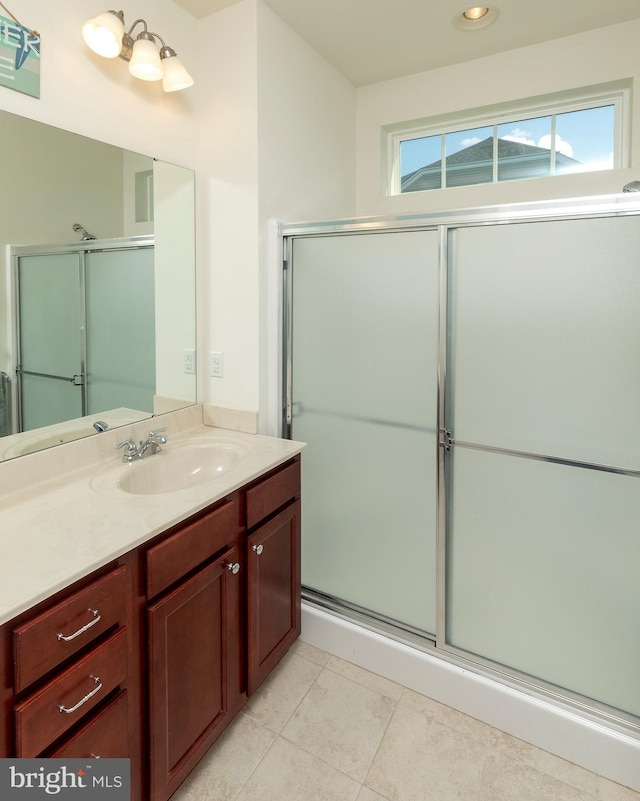 bathroom with tile patterned flooring, vanity, and walk in shower