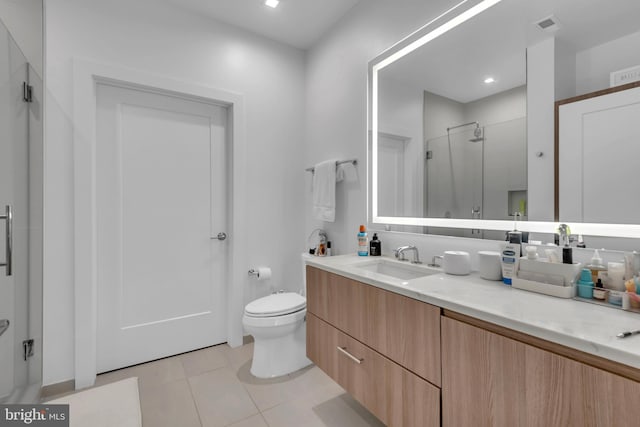 bathroom featuring tile patterned flooring, vanity, toilet, and a shower with shower door