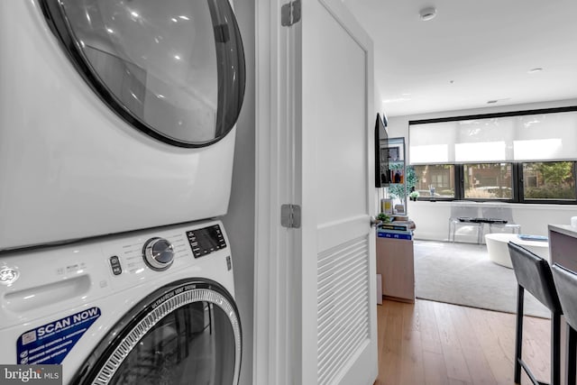 laundry room featuring light hardwood / wood-style flooring and stacked washing maching and dryer