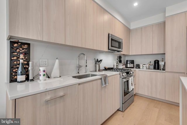 kitchen with light brown cabinetry, stainless steel appliances, and sink