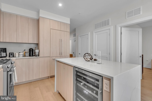 kitchen featuring electric range, a center island, light brown cabinets, beverage cooler, and light stone counters