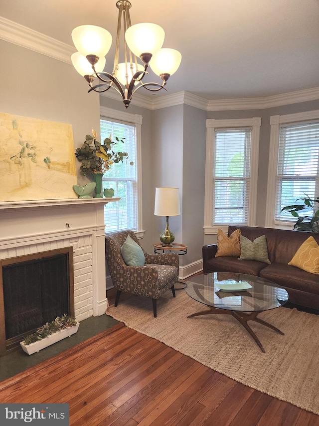 living room with an inviting chandelier, hardwood / wood-style flooring, a fireplace, and ornamental molding