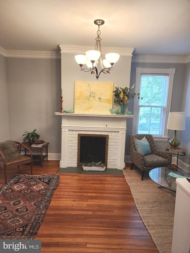 living room with a notable chandelier, ornamental molding, dark wood-type flooring, and a fireplace