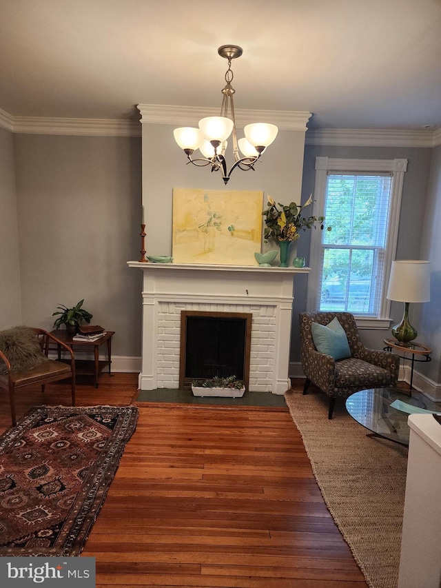 living room featuring crown molding, dark hardwood / wood-style floors, a chandelier, and a brick fireplace