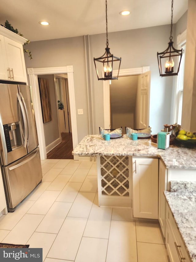 kitchen featuring pendant lighting, white cabinetry, light stone countertops, and stainless steel fridge with ice dispenser