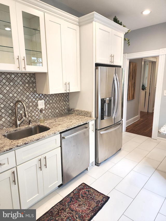 kitchen featuring appliances with stainless steel finishes, sink, light stone counters, and white cabinets