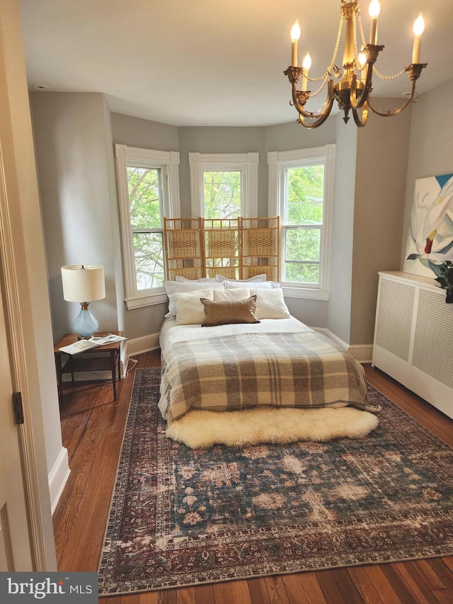 bedroom featuring radiator, a notable chandelier, and dark wood-type flooring