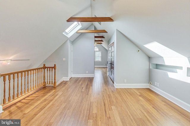 bonus room featuring lofted ceiling with skylight and light hardwood / wood-style floors