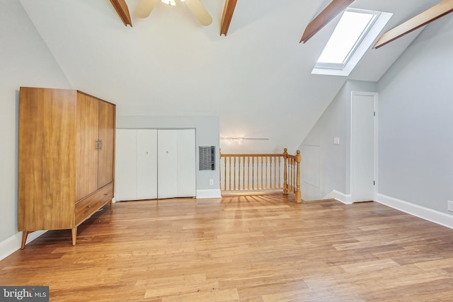 unfurnished living room with light hardwood / wood-style flooring, vaulted ceiling with skylight, ceiling fan, and electric panel