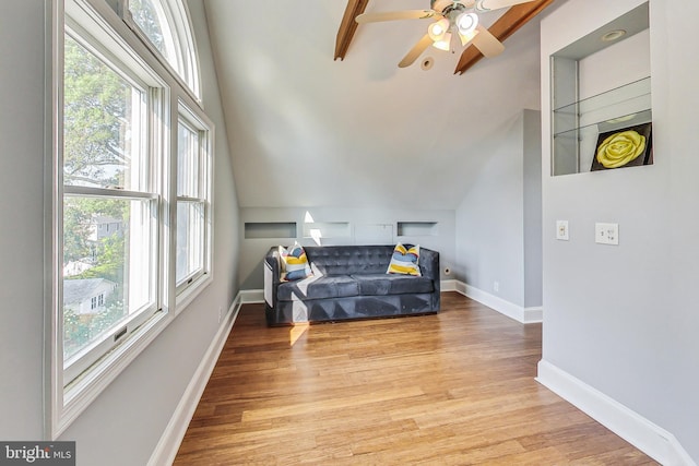 living area with a wealth of natural light, vaulted ceiling, ceiling fan, and light wood-type flooring