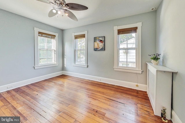 spare room featuring a healthy amount of sunlight, light hardwood / wood-style floors, and ceiling fan