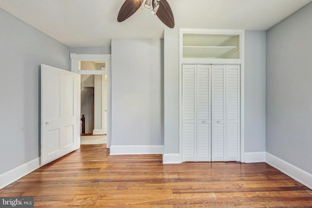 unfurnished bedroom featuring ceiling fan, hardwood / wood-style flooring, and a closet