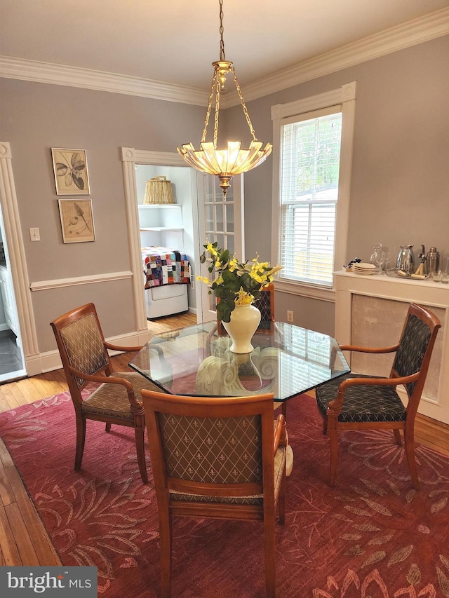 dining space with ornamental molding, a notable chandelier, and hardwood / wood-style flooring