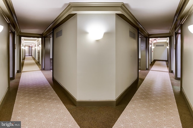 hall with ornamental molding, visible vents, and baseboards