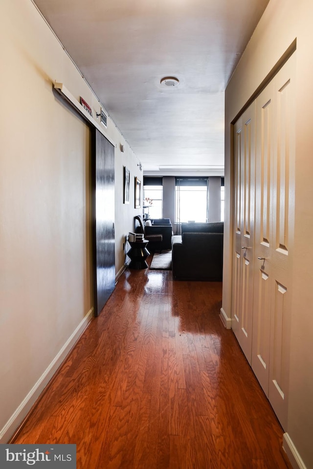 hallway featuring visible vents, baseboards, and wood finished floors