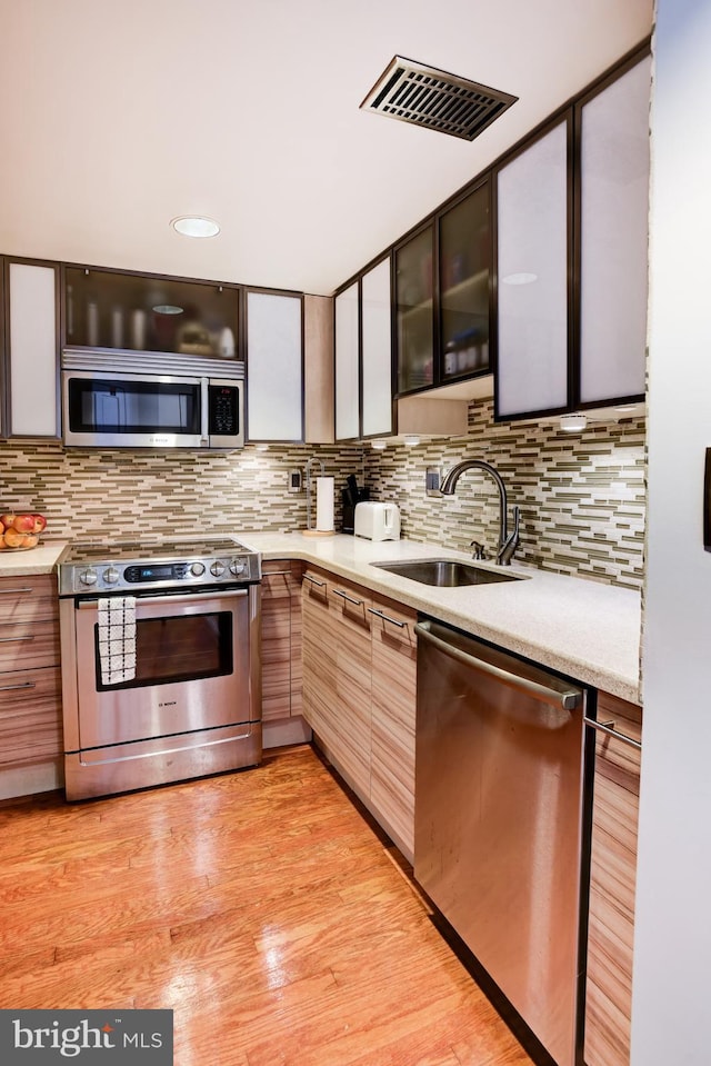 kitchen with a sink, visible vents, light countertops, appliances with stainless steel finishes, and backsplash