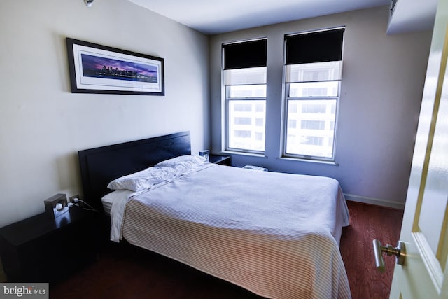 bedroom featuring baseboards and dark wood-type flooring