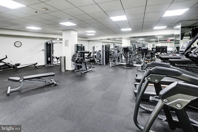 gym with a paneled ceiling and baseboards