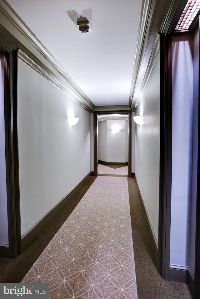 hallway featuring carpet floors, baseboards, and crown molding