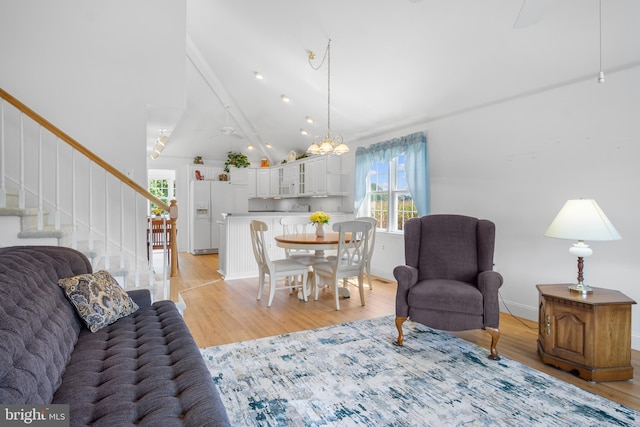 living room with light hardwood / wood-style flooring, a notable chandelier, beamed ceiling, and high vaulted ceiling