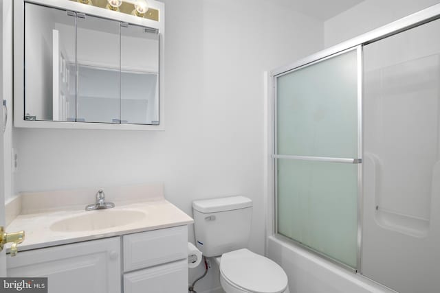 full bathroom with combined bath / shower with glass door, vanity, and toilet