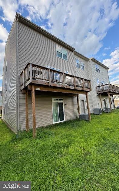 back of property with a yard, a deck, and central air condition unit