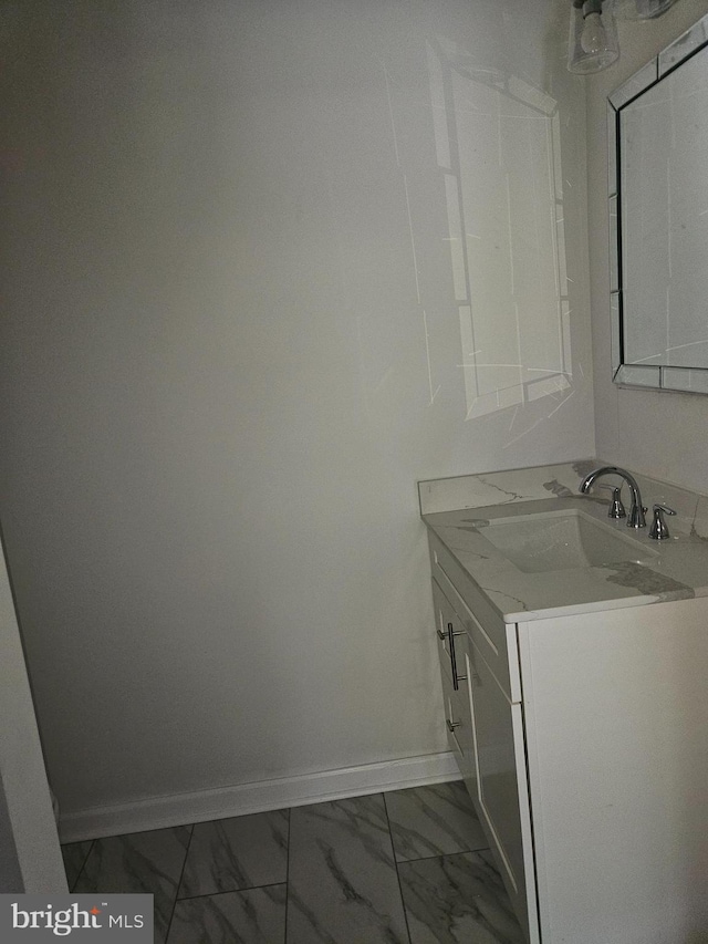 bathroom with marble finish floor, vanity, and baseboards