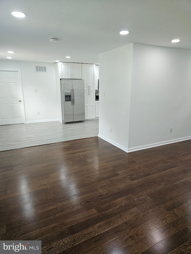 empty room featuring dark wood-style floors, visible vents, and baseboards