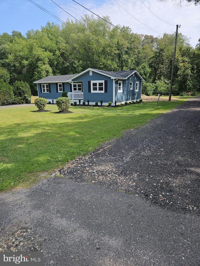 view of front of home with a front yard and a forest view