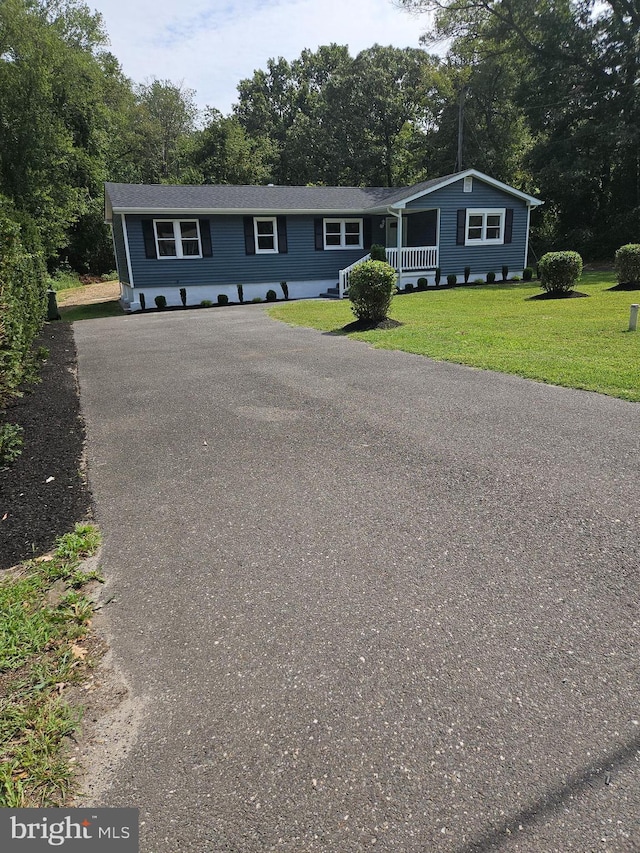 view of front of property featuring a front yard, covered porch, and driveway