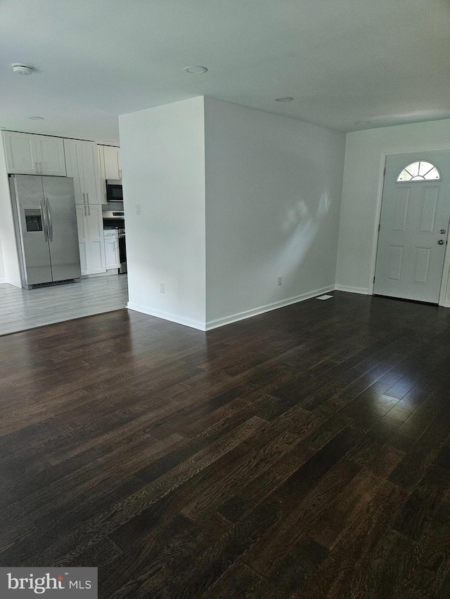 unfurnished living room featuring dark wood-style floors and baseboards