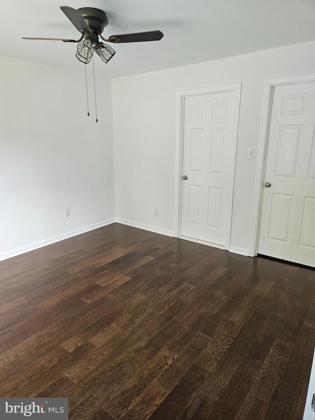 unfurnished room featuring a ceiling fan, baseboards, and dark wood-type flooring