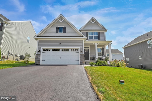 craftsman-style home with cooling unit, a garage, covered porch, and a front yard