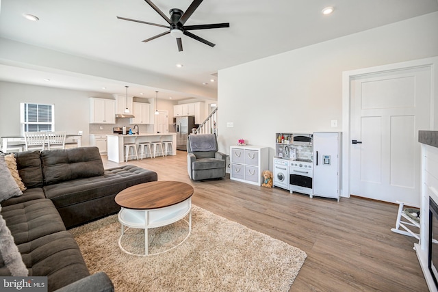 living room with ceiling fan, sink, and light hardwood / wood-style floors