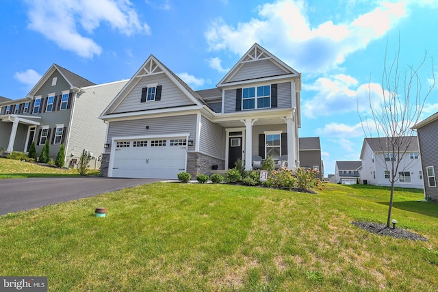 craftsman-style home with covered porch, a garage, and a front lawn