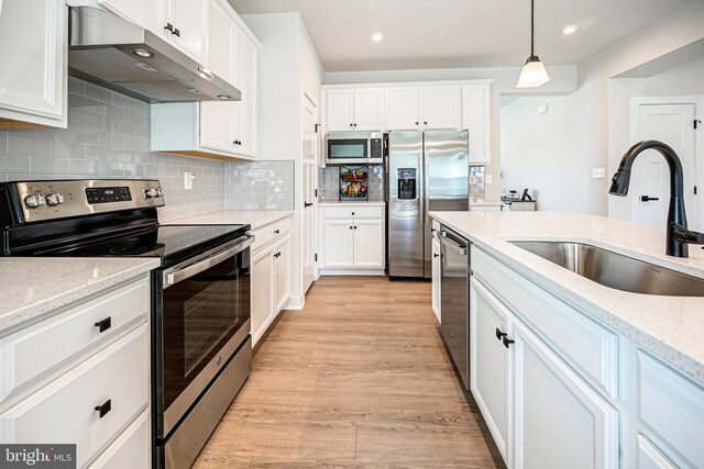 kitchen featuring pendant lighting, stainless steel appliances, light hardwood / wood-style floors, and sink