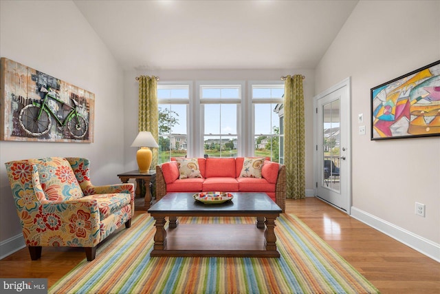 living area with a healthy amount of sunlight, baseboards, vaulted ceiling, and wood finished floors