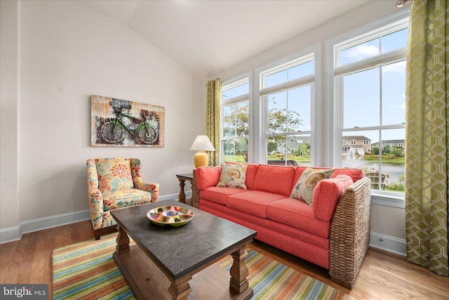 living room featuring lofted ceiling, baseboards, and wood finished floors