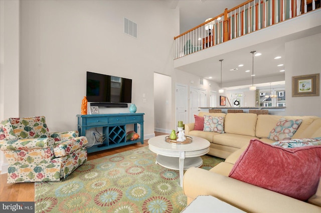 living room with a towering ceiling and wood-type flooring