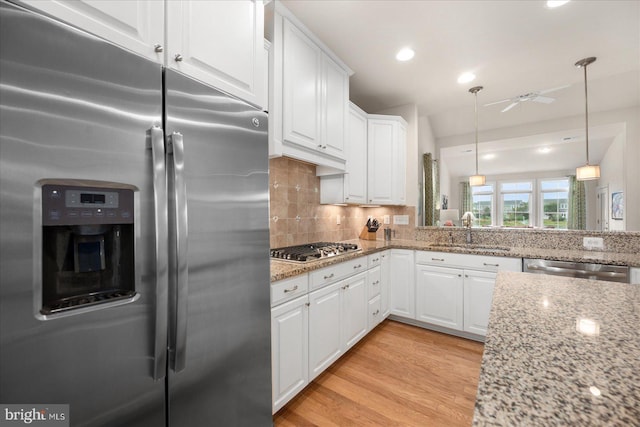 kitchen with light hardwood / wood-style flooring, appliances with stainless steel finishes, white cabinetry, ceiling fan, and pendant lighting