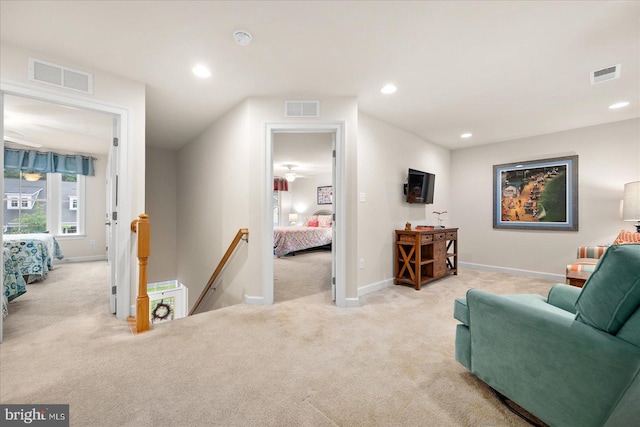 living area featuring carpet, visible vents, and an upstairs landing