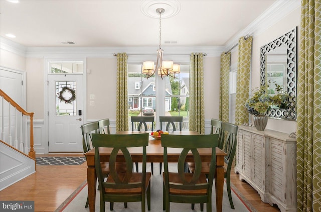 dining area featuring wood-type flooring, an inviting chandelier, and crown molding