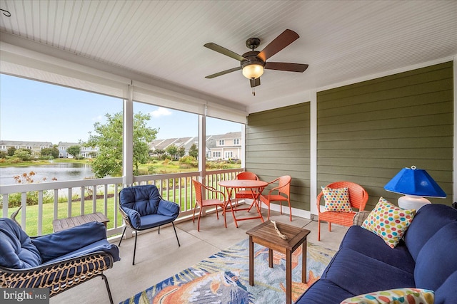 sunroom with a healthy amount of sunlight, ceiling fan, and a water view